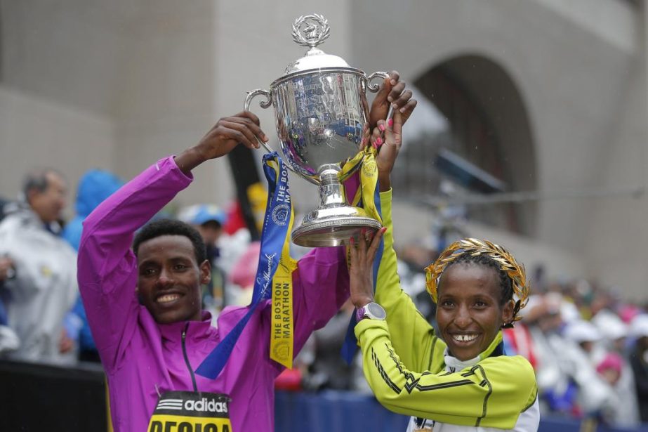Men's division winner Lelisa Desisa of Ethiopia (L) and women's division winner Caroline Rotich of Kenya pose with the trophy at the finish line of the 119th Boston Marathon in Boston, Massachusetts on Monday.