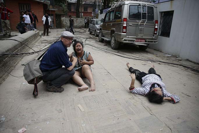 A man comforts a woman next to a seriously injured person on the ground in the aftermath of the disaster which is thought to have killed at least two .