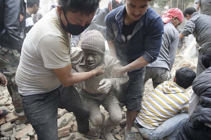 Locals rescue a dust-covered man from the the rubble of a destroyed building, as they work to find and rescue any survivors of the disaster.