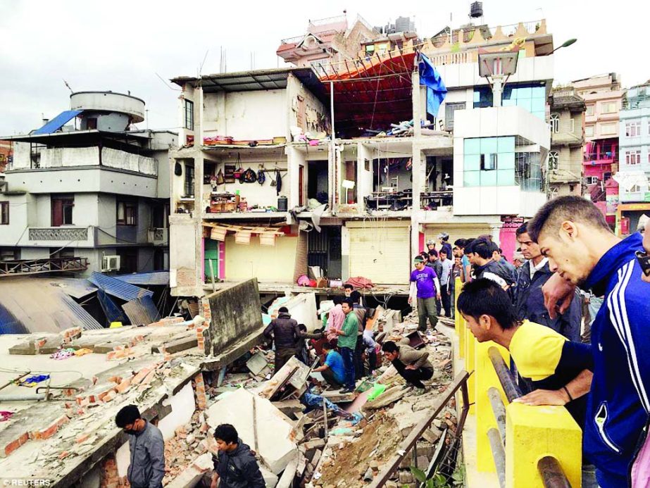 People survey a site damaged by the earthquake measuring 7.8 magnitude which struck west of the ancient Nepali capital of Kathmandu on Saturday, killing more than 1000 people, injuring hundreds and leaving a pall over the valley, doctors and witnesses sai