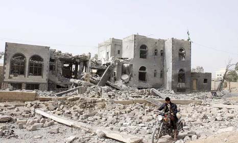 A man rides motorcycle past a headquarters of Houti group, which was destroyed after an air strike by a Saudi-led coalition, in Saada.