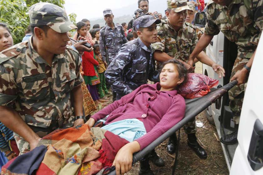 Sita Karka, suffering two broken legs from Saturday's massive earthquake, is assisted into an ambulance by Nepalese soldiers and police after arriving by helicopter from the heavily-damaged Ranachour village at a landing zone in the town of Gorkha, Nepal