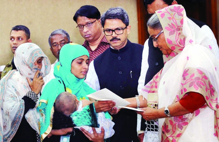 Prime Minister Sheikh Hasina distributing cheques of financial assistance among the family members of those who died and got injured during blockade and hartal enforced by BNP-led 20-party alliance at her office on Wednesday. BSS photo