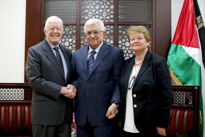 Former prime minister of Norway Gro Harlem Brundtland stands next to Palestinian President Mahmoud Abbas (C) as he shakes hands with former US president Jimmy Carter during their meeting in the West Bank city of Ramallah