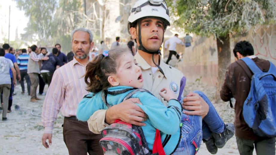 A civil defence member holds a rescued schoolgirl after what activists said was a barrel-bomb attack in a residential area of Aleppo.