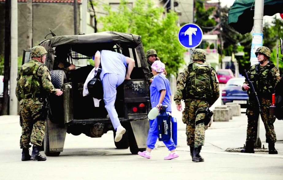 Medical personnel enter a police vehicle at a police checkpoint in Kumanovo, Macedonia on Saturday.