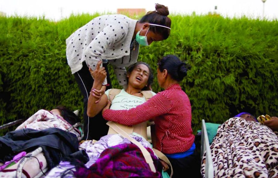 An earthquake victim reacts in pain after being moved out from the hospital to the open ground for treatment, in Kathmandu.