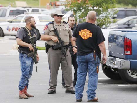 Law enforcement officers talk to a man near the parking lot of a Twin Peaks Restaurant on Sunday in Waco, Texas, after a shooting involving rival biker gangs. Waco police Sgt. W. Patrick Swanton told KWTX-TV there were "multiple victims" after gunfire e