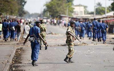Policemen and soldiers walk on a street during a protest against Burundi President Pierre Nkurunziza and his bid for a third term in Bujumbura, Burundi