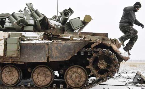 A Ukrainian serviceman jumps off a tank damaged during fighting with pro-Russian separatist forces.