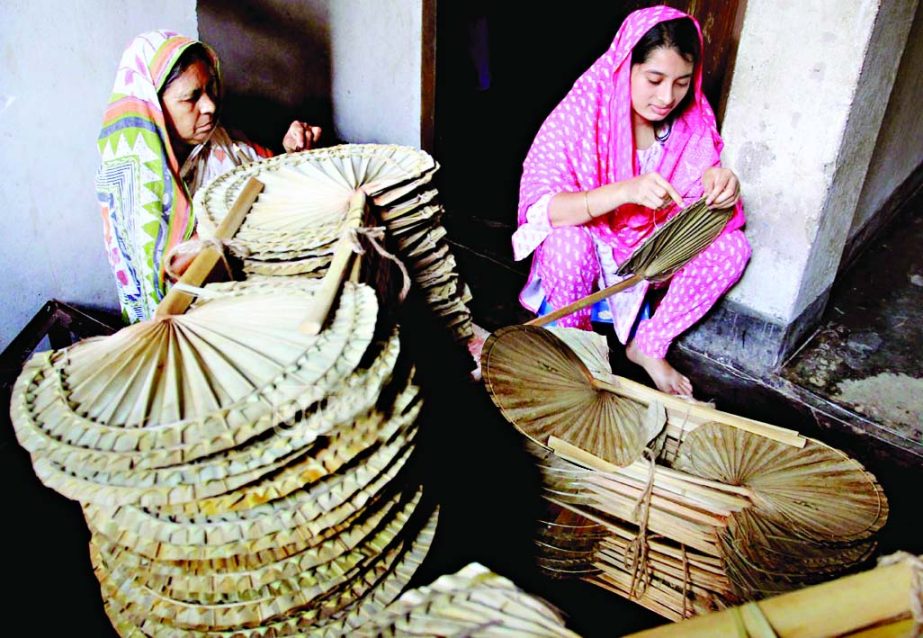 Two rural women seen busy making hand-fans to sell those during the on going summer. This photo was taken from city's Nutan Bazar area under Bhatara thana in city on Friday.
