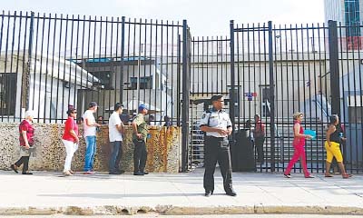 A security guard stands outside the US Interests section compound as people line up to apply for visa in Cuba's capital on Friday.