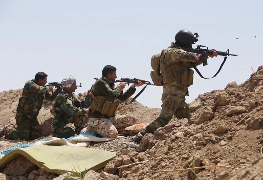 Iraqi soldiers and Shiite fighters from the popular committees fire towards Islamic State (IS) positions in the Garma district of Anbar province.