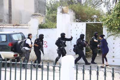 Tunisian anti-terrorism brigade personnel enter a house to take position after a shooting at the Bouchoucha military base in Tunis.