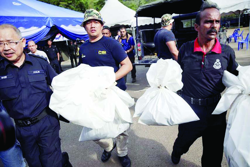 Forensic experts collected bags of human remains on Monday that were found at the site of mass graves in northern Malaysia.