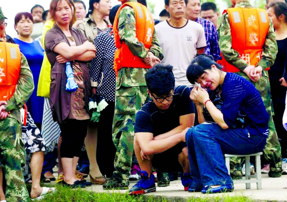 A relative Â® of a passenger - missing after a Chinese cruise ship capsized on the Yangtze river - wipes away tears as she and other relatives gather at the disaster site in Jianli, central Hubei province on Wednesday.