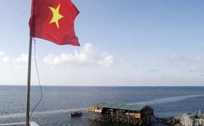 A Vietnamese flag flutters as a motorboat transporting Vietnamese navy personnel passes a construction site of a new pier on Truong Sa islands or Spratly islands.