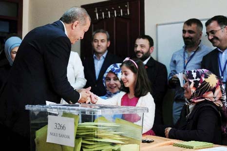 Turkish President Recep Tayyip Erdogan (L) shakes hands with a girl after voting in Turkey's general election at a polling station in Istanbul on Sunday.
