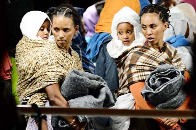 Migrants and their children wait to disembark from the "Phoenix"" ship upon their arrival in the port of Augusta on the eastern coast of Sicily on Sunday."