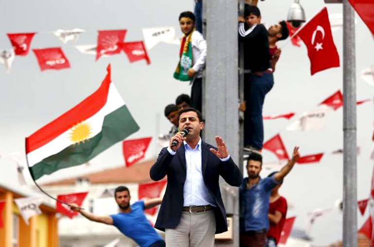 Selahattin Demirtas, co-chairman of the pro-Kurdish Peoples' Democratic Party (HDP), speaks as his supporters wave Kurdish (L) and Turkish national Â® flags in the background.