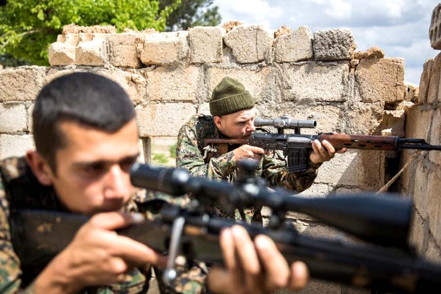 Kurdish fighters shoot at jihadists during clashes on the the outskirts of the Syrian town of Tal Tamr.