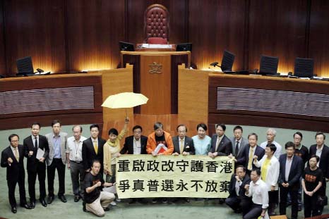 Pro-democracy lawmakers display a yellow umbrella and a banner stating "Reopen political reform to protect Hong Kong, never give up to fight for true universal suffrage" after 28 lawmakers voted against the election reforms proposals at the Legislative