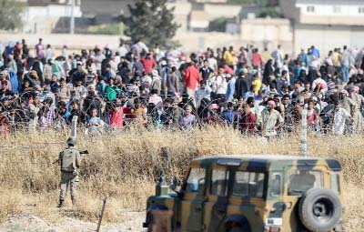 Thousands of refugees stand on the Syrian side of the Turkish Akcakale crossing gate in Sanliurfa province after running away from central Tal Abyad.