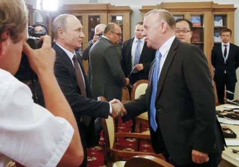 Russian President Vladimir Putin, left, shakes hands with Associated Press VP and Director of Global Video News Sandy MacIntyre at the St. Petersburg International Investment Forum in St.Petersburg, Russia on Friday