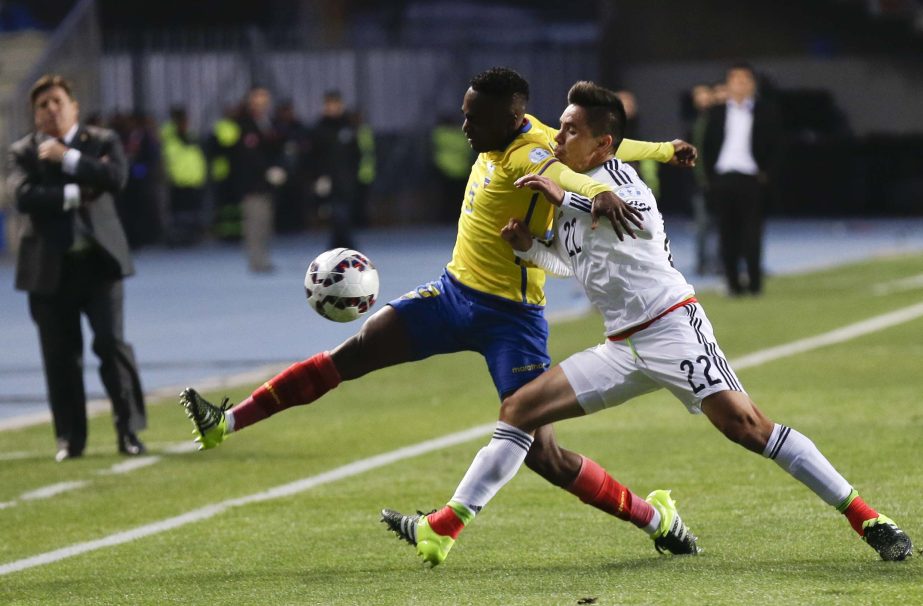 Mexico's Efrain Velarde (right) fights for the ball against Ecuador's Renato Ibarra, center, as Mexico's coach Miguel Herrera (left) looks on during a Copa America Group A soccer match at El Teniente Stadium in Rancagua, Chile on Friday.