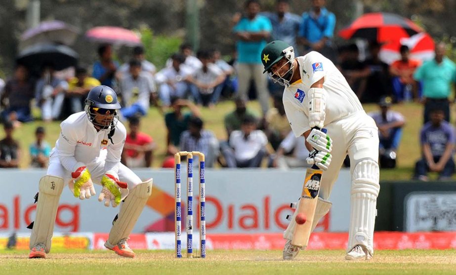 Pakistan cricketer Zulfiqar Babar (R) plays a shot as Sri Lankan wicketkeeper Dinesh Chandimal looks on during the fourth day of the opening Test match between Sri Lanka and Pakistan at the Galle International Cricket Stadium in Galle on Saturday.