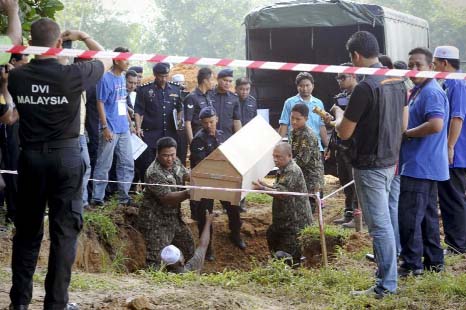 Malaysian police carries a coffin containing the remains of a Rohingya migrant for a mass burial ceremony in Kedah, Malaysia on Monday.