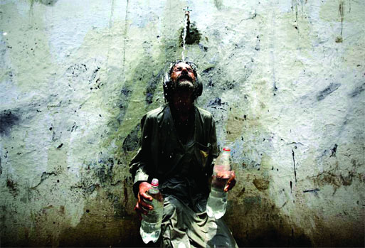 A man cools off from a public tap after filling bottles during intense hot weather in Karachi