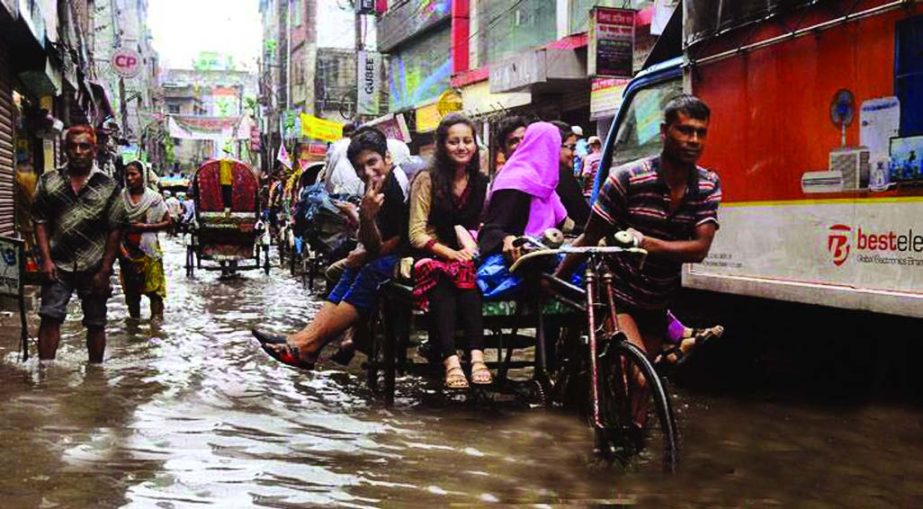 Drains over flooded: Waterlogging on many streets in the capital following heavy monsoon rains paralysed life. Photo shows school students passing through flooded Siddique Bazar area on Friday morning.