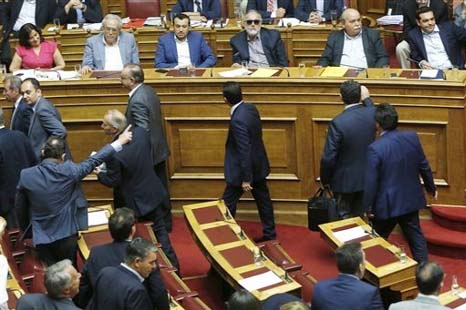 Greece's Prime Minister Alexis Tsipras, right background, looks on as the lawmakers of the New Democracy right party leave an emergency Parliament session for the governmentâ€™s proposed referendum in Athens, early Sunday.