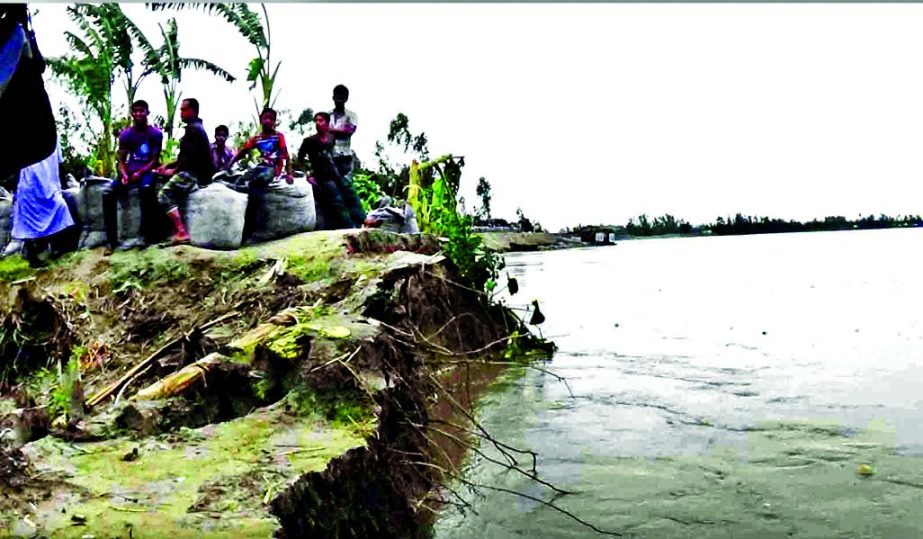 River erosion took serious turn as flood waters started receding with the stoppage of rains. Photo shows local residents waiting with their homesteads on the bank of the river in Gaibandha on Monday.