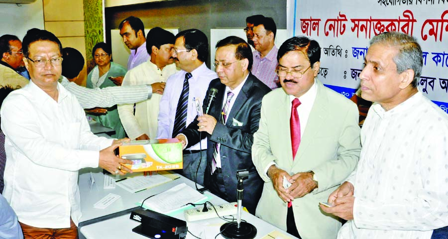 Federation of Bangladesh Chambers of Commerce and Industry President Abdul Motlub Ahmad and Deputy Governors of Bangladesh Bank Md Abul Kashem and Shuvankar Shaha handing over fake note detector machine to shop owners.