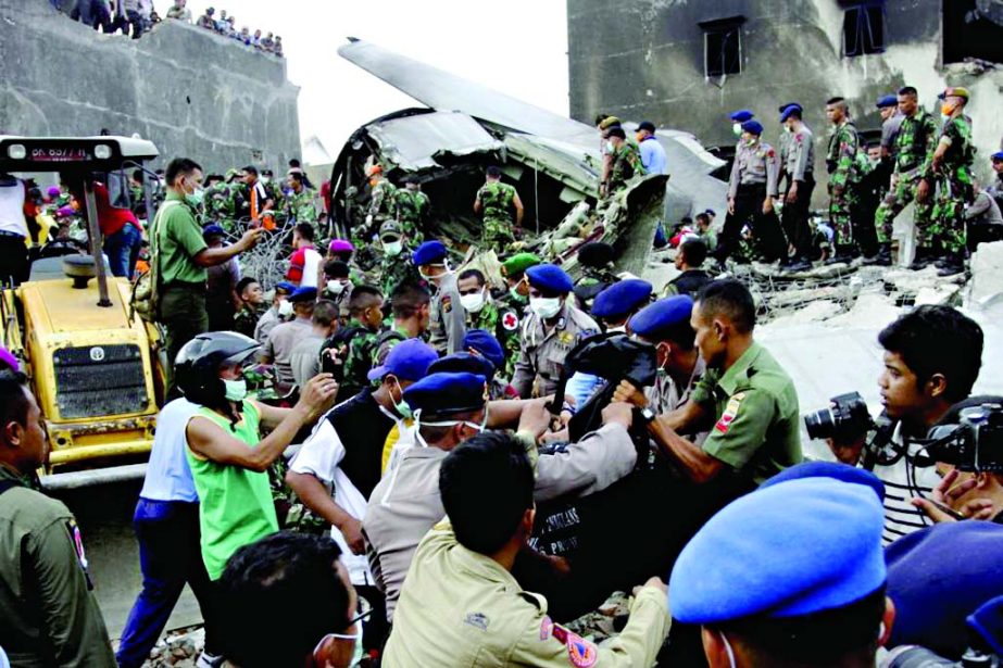 Security forces and rescue teams remove the bodies of victims from the wreckage of an Indonesian military C-130 Hercules transport plane after it crashed into a residential area in the North Sumatra city of Medan, Indonesia on Tuesday.