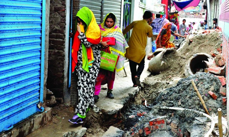 Road digging by various service bodies including WASA in city during monsoon rains caused immense sufferings to the city dwellers. Photo shows local residents passing through a virtually damaged spot adjacent to WASA's work site at Mir Hazirbagh area on