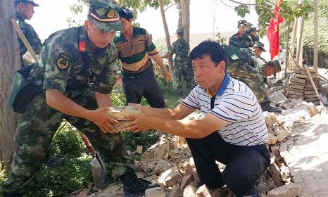 Rescues help villagers dismantle a damaged wall after an earthquake hit the area in Pishan county in Halian in China's northeast Xinjiang region on Friday.