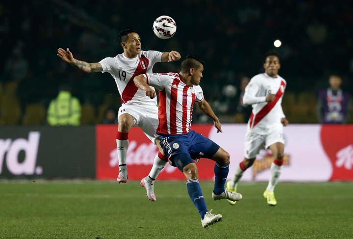 Peru's Yoshimar Yotun jumps for the ball with Paraguay's Miguel Angel Samudio during the soccer match for the third place of the Copa America at the Ester Roa Rebolledo Stadium in Concepcion, Chile on Friday.