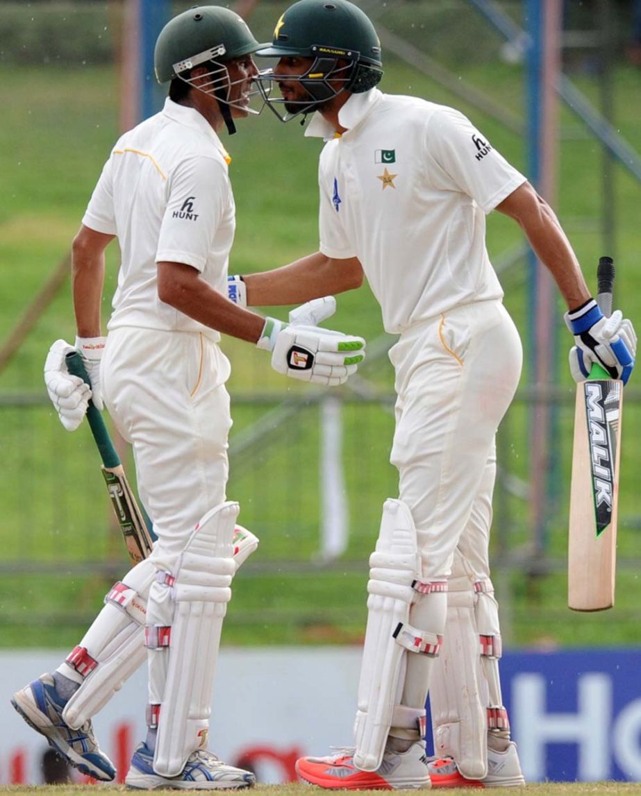 Pakistan cricketer Shan Masood (R) is congratulated by teammate Younis Khan after scoring a half-century (50 runs) on the fourth day of the third and final Test match between Sri Lanka and Pakistan at the Pallekele International Cricket Stadium in Palleke