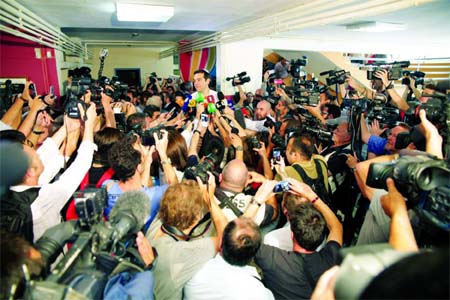 Greece's Prime Minister Alexis Tsipras, center, speaks to the media after voting at a polling station in Athens. Greeks began voting on Sunday in a closely-watched, closely-contested referendum, which the government pits as a choice over whether to defy