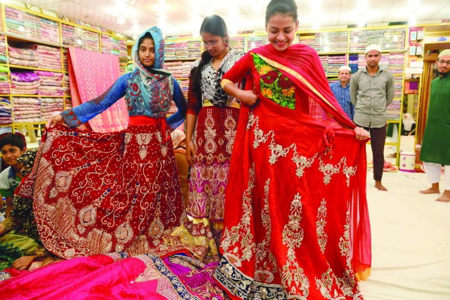 Smiling girls pose with their favourite dress lehenga at Hanif Silk Benarasi Palli, Mirpur in the city on Friday. The lehenga prices are from 40,000 to 1lakh 70,000.