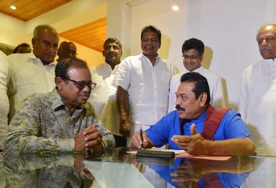 Former Sri Lankan leader Mahinda Rajapakse (R) signs nomination papers as party general secretary Susil Premajayantha looks on at his home in a suburb of Colombo