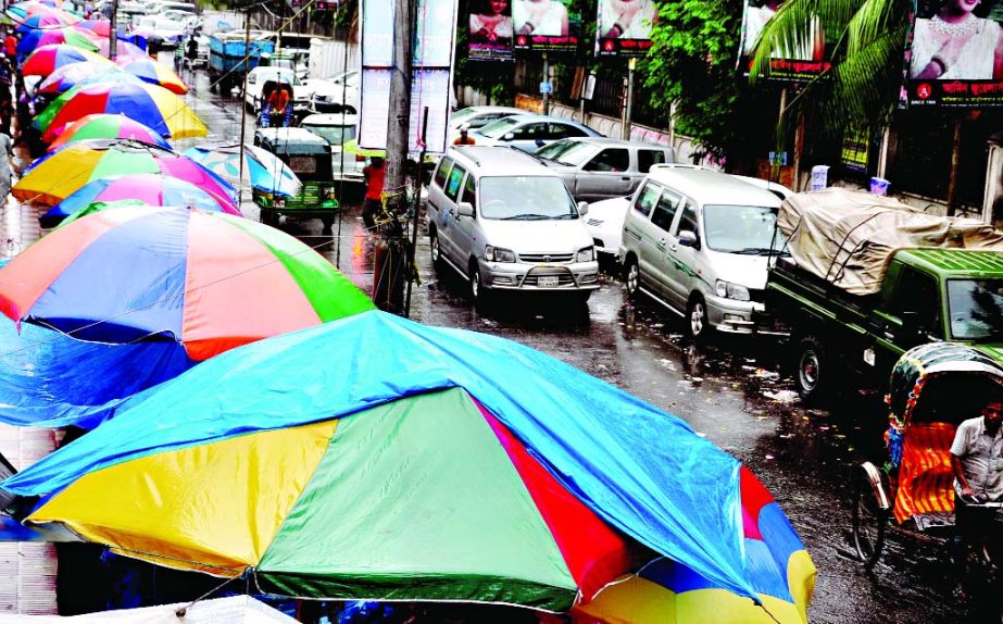 Both sides of the thoroughfare around Baitul Mukarram Market have been illegally occupied for makeshift shops and parking cars. This photo was taken during rains on Friday afternoon.