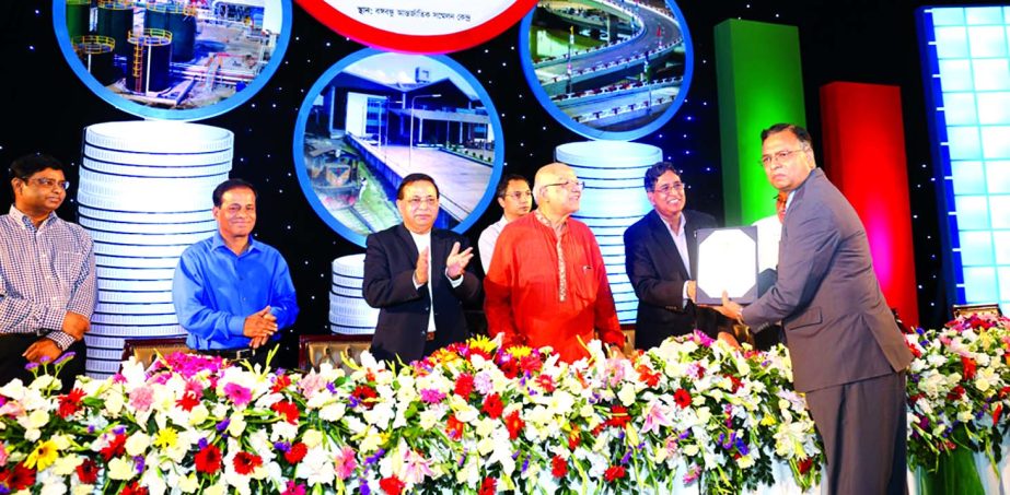 Finance Minister Abul Maal Abdul Muhith handing over the highest VAT payer's crest to Choudhury Atiur Rasul, Director (Accounts) of PRAN-RFL Group at Bangabandhu International Conference Center in the city on Sunday. Farid Uddin, member of NBR, presided