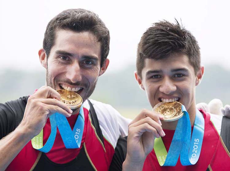 Mexico's Alan Armenta, left, and Alexis Lopez bite their gold medals after winning the men's lightweight double sculls at the Pan Am Games in St. Catharines, Ontario on Tuesday.