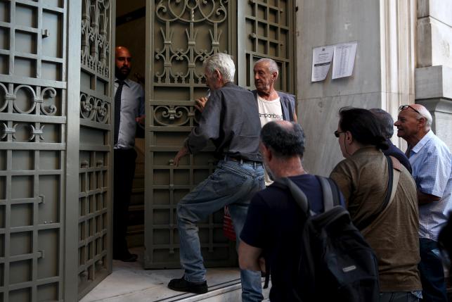 A National Bank official opens the door of a bank branch while people wait to enter in Athens, Greece July 20, 2015. ReutersYiannis Kourtoglou