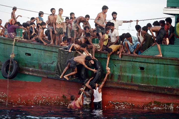 Rohingya migrants pass food supplies dropped by a Thai army helicopter to others aboard a boat drifting in Thai waters off the southern island of Koh Lipe in the Andaman sea.