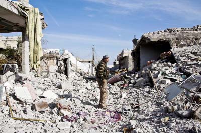 A Kurdish People's Protection Units (YPG) fighter stands in the rubble of Kobani, Syria.